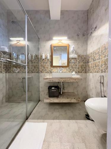 a bathroom with a shower and a sink and a toilet at Cochrane Place By Teesta Hotels in Kurseong