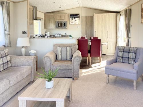a living room with couches and chairs and a kitchen at Ballagan Lodge - Uk43375 in Leanach