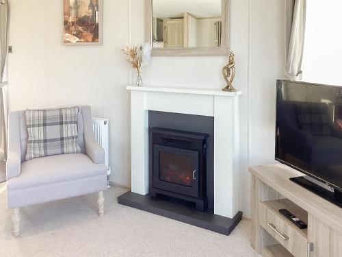 a living room with a fireplace and a tv at Ballagan Lodge - Uk43375 in Leanach