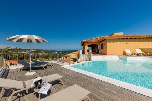 a swimming pool with chairs and an umbrella next to a house at Hotel Marana in Golfo Aranci