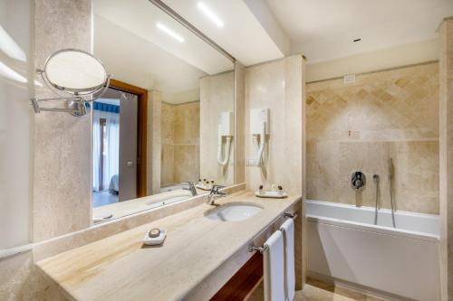 a bathroom with a sink and a tub and a mirror at Hotel Marana in Golfo Aranci