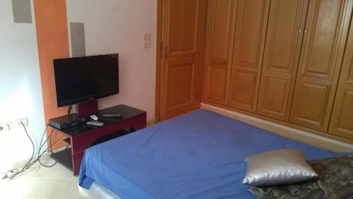 Schlafzimmer mit einem Bett und einem Flachbild-TV in der Unterkunft Résidence Tasnim in Ariana