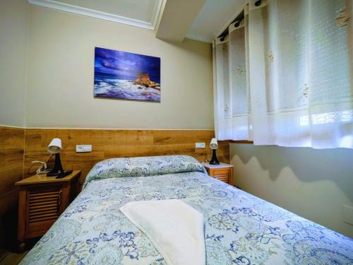 ein Schlafzimmer mit einem Bett, zwei Lampen und einem Fenster in der Unterkunft Alojamientos ALBOR I in Gijón