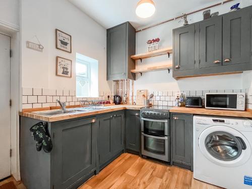 a kitchen with gray cabinets and a washer and dryer at The Badger Sett in Hinderwell