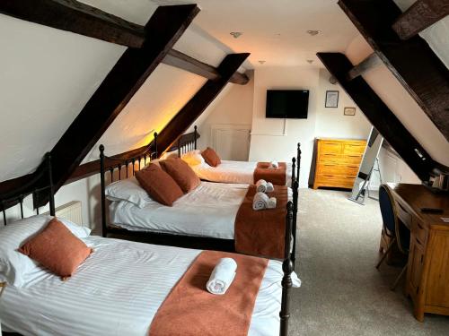 a bedroom with two beds and a tv in a room at The Berkeley Arms Hotel in Berkeley
