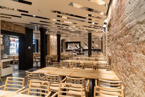 a restaurant with wooden tables and chairs and a brick wall at Barcelona House in Barcelona