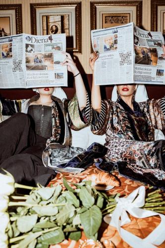 Twee vrouwen zitten in bed kranten te lezen. bij The Benjamin House in Rīga