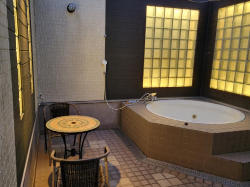 ein Badezimmer mit Badewanne und einem Tisch und einem Tisch und einem Tisch in der Unterkunft HOTEL KAZAN (Adult Only) in Iwaki