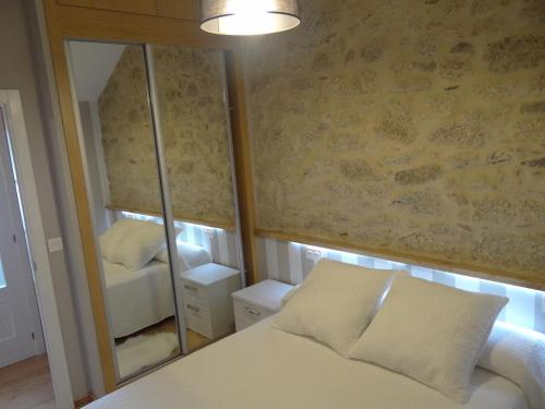 1 dormitorio con espejo, 1 cama y 1 silla en Casa do Forno, en Castro de Oro
