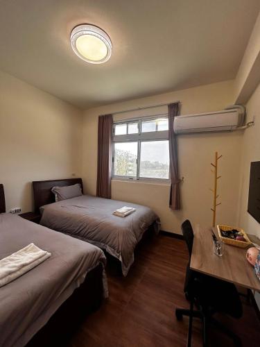 a room with two beds and a table and a window at Kinmen Xinya Homestay in Jinning