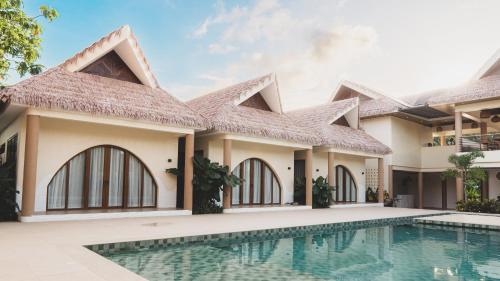 a house with a swimming pool in front of it at Sunyata Resort Siargao in Catagnan