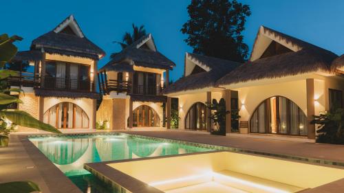 a villa with a swimming pool at night at Sunyata Resort Siargao in Catagnan