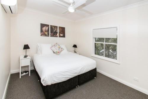 a white bedroom with a bed and a window at Villa in the Valley in Pokolbin