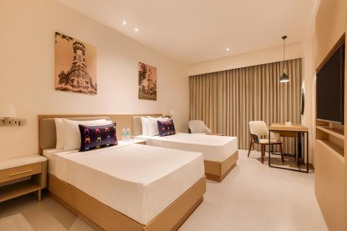 a hotel room with two beds and a desk at Keys Select By Lemon Tree Hotels, Vadodara in Vadodara
