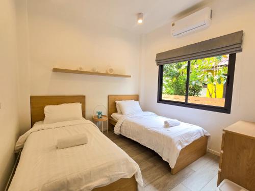 two beds in a room with a window at AURA STAY - HeyLanna Private Family Pool Villa near Kad Farang in Chiang Mai