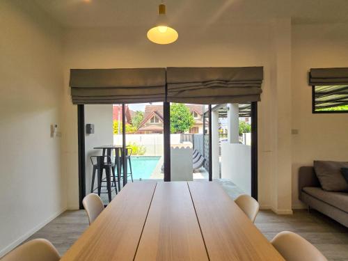 a living room with a wooden table and a couch at AURA STAY - HeyLanna Private Family Pool Villa near Kad Farang in Chiang Mai