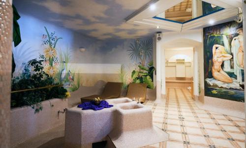 a living room with a couch and paintings on the wall at Hotel Enzian by Alpeffect Hotels in Zauchensee