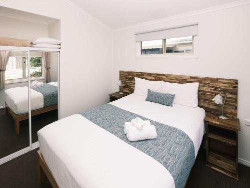 a bedroom with a large white bed and a mirror at BIG4 Middleton Beach Holiday Park in Albany