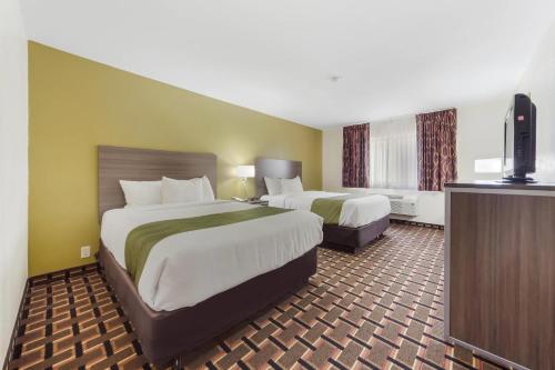 a hotel room with two beds and a flat screen tv at Quality Inn Lincoln Cornhusker in Lincoln