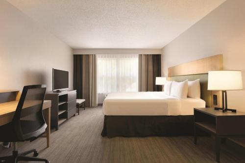 a hotel room with a bed and a desk at Country Inn & Suites by Radisson, Champaign North, IL in Champaign