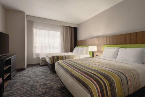 a hotel room with two beds and a television at Country Inn & Suites by Radisson, Champaign North, IL in Champaign