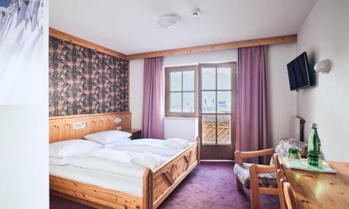 a hotel room with a bed and a window at Hotel Enzian by Alpeffect Hotels in Zauchensee