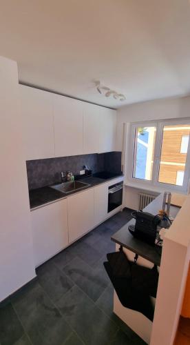 a kitchen with white cabinets and a sink and a table at Hollandia 26 in Riederalp