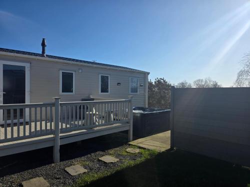 a house with a wooden deck and a fence at Dixons Den Hot Tub in Swarland