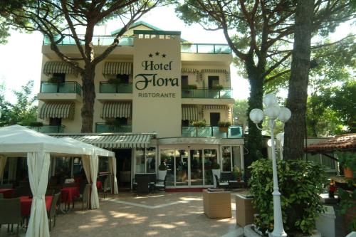 a hotel with tables and chairs in front of a building at Hotel Flora in Milano Marittima