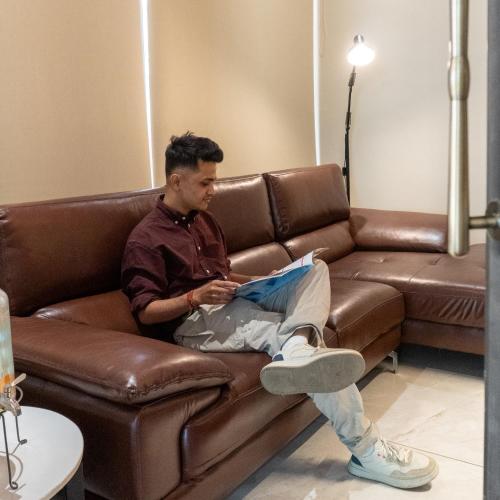 ein Mann sitzt auf einer Couch und liest ein Buch in der Unterkunft Hotel AM PM in Bhubaneshwar