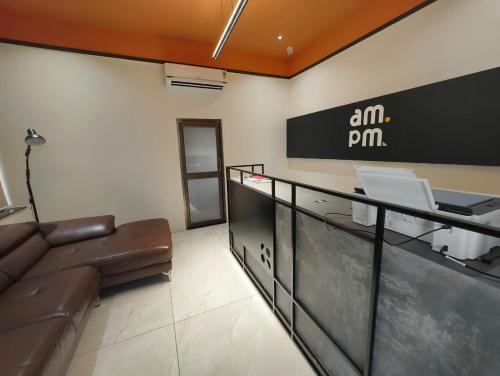 Eine Lobby mit einer Couch und einem AMM-Schild an der Wand in der Unterkunft Hotel AM PM in Bhubaneshwar