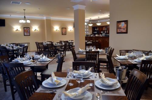 奧拉迪亞的住宿－Vila Gardenia，餐厅设有木桌、椅子、盘子和餐巾