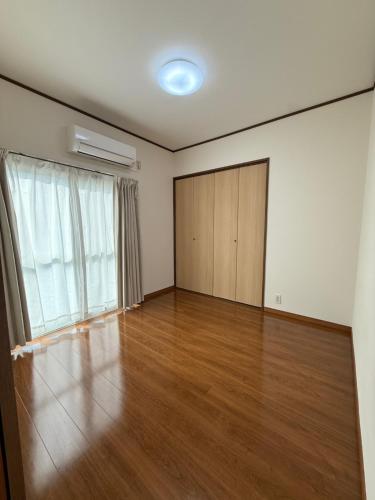 an empty room with a hard wood floor and a door at 宿Oshikiri 04 in Shibushi