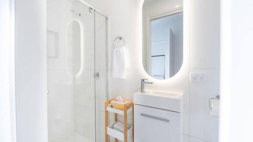 a white bathroom with a sink and a shower at Nouvelle Studio in Epsom