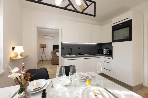 a white kitchen with a table with plates and wine glasses at Apartments Lia in Ljubljana