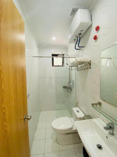 a white bathroom with a toilet and a sink at Hotel 24h in Hai Phong