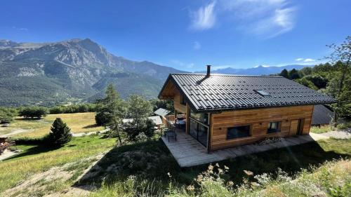 a wooden house on a hill with mountains in the background at Chalet - Superbe Chalet 12 pers MAE-2644 in Les Prés