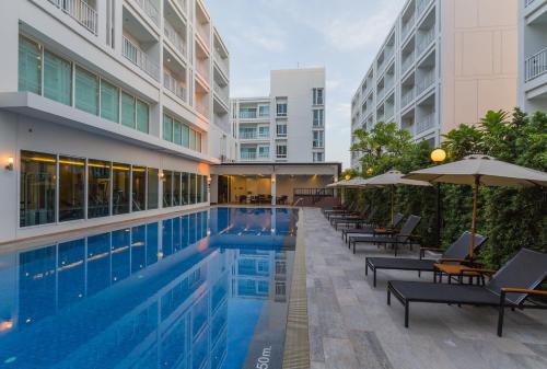 a swimming pool with chairs and umbrellas next to a building at Kantary 304 Hotel Prachinburi in Si Maha Phot