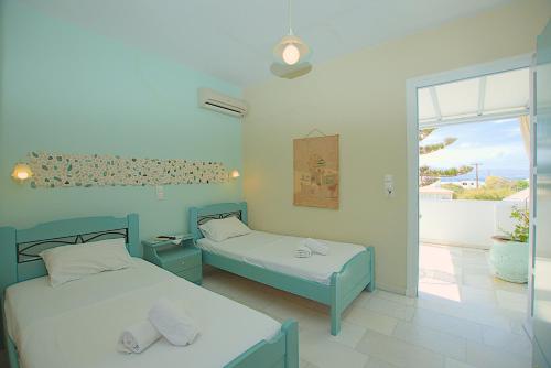 a bedroom with two beds and a balcony with a view at Maroussa Studios in Agia Anna Naxos