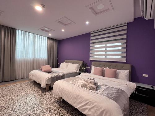 two beds in a room with purple walls at Aren Inn in Zhushan