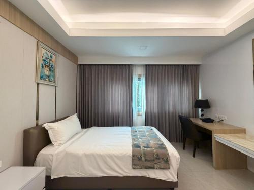 a hotel room with a bed and a desk at Palette Luxe Jomtien Beach Pattaya in Jomtien Beach
