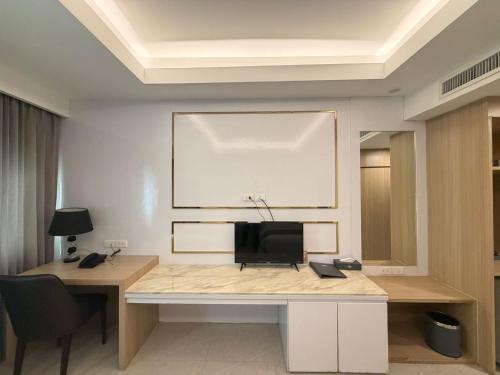 a room with a desk with a television on a wall at Palette Luxe Jomtien Beach Pattaya in Jomtien Beach