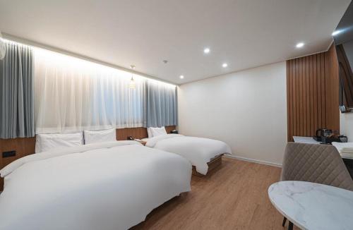a hotel room with two beds and a table at Daejeon Comma Hotel in Daejeon