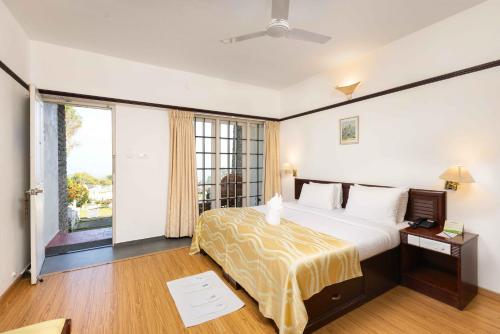 a hotel room with a bed and a large window at The Siena Village in Chinnakanal
