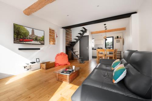 a living room with a black leather couch at Beautiful House avec AC climatisation - terrasse privée - Côté pavé centre-ville Toulouse in Toulouse