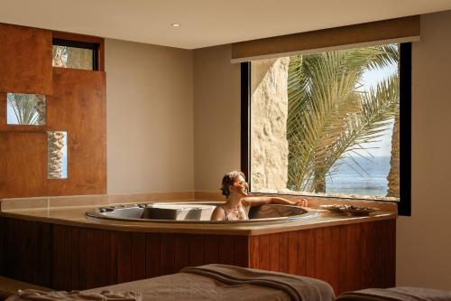 a woman in a bath tub with a window at The Makadi Spa Hotel - Couples Only 18 Years Plus in Hurghada