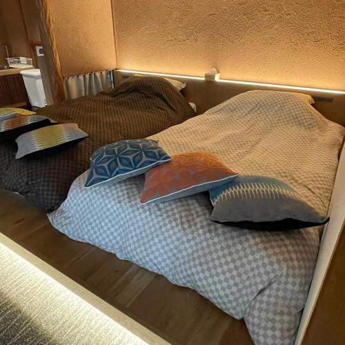 a bed with three pillows on top of it at お宿 垢田の杜　桂月 in Hatabu