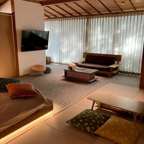 a living room with a couch and a tv at お宿 垢田の杜　桂月 in Hatabu