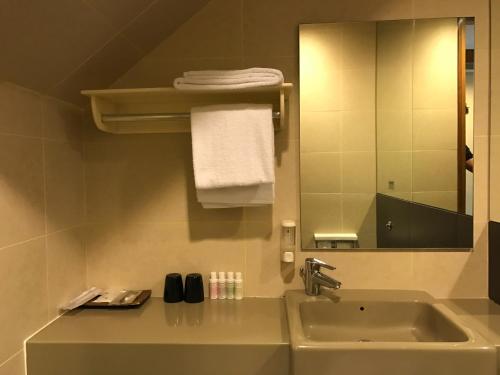 Siloso Beach Resort - Sentosa في سنغافورة: حمام مع حوض ومرآة