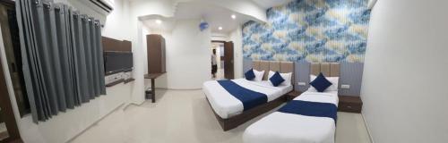 una camera da letto con due letti con cuscini blu e bianchi di Hotel New Rest Inn a Mahesāna